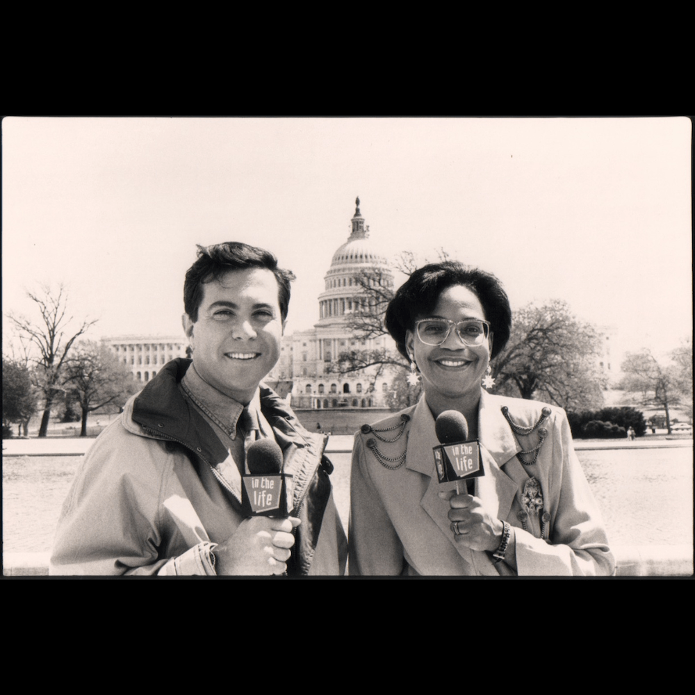 Hosts of In The Life (Garrett Glaser, Karen Williams) holding microphones in front of the U.S. Capitol during the 1993 episode on the March on Washington for Lesbian, Gay, and Bi Equal Rights and Liberation.